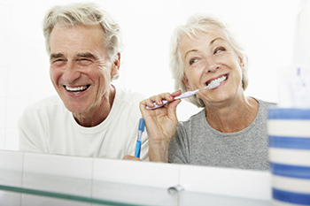 Couple in bathroom with woman brushing her teeth
